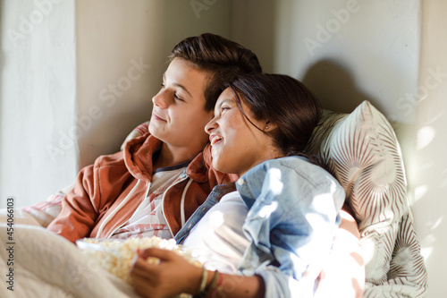 Teenage couple lying in bed and watching tv