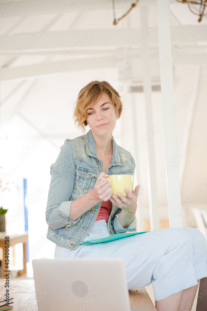 Portrait of woman sitting at desk with laptop and cup in office Portrait of woman sitting at desk with laptop and cup in office