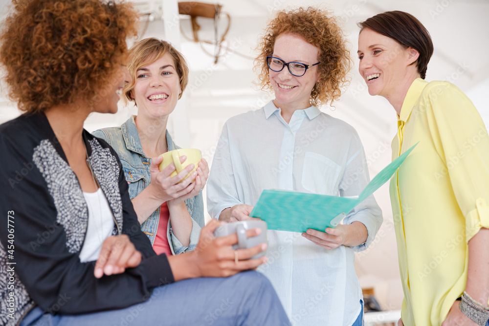 Women with coffe cup talking in office