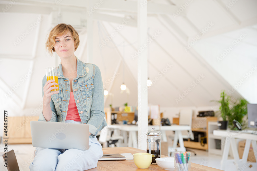 Portrait of woman sitting at desk with laptop in office Portrait of woman sitting at desk with laptop in office