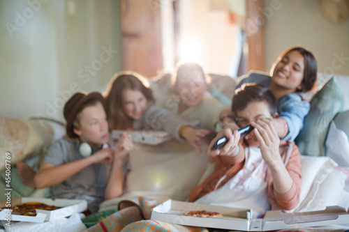 Group of teenagers opening pizza boxes on sofa in living room