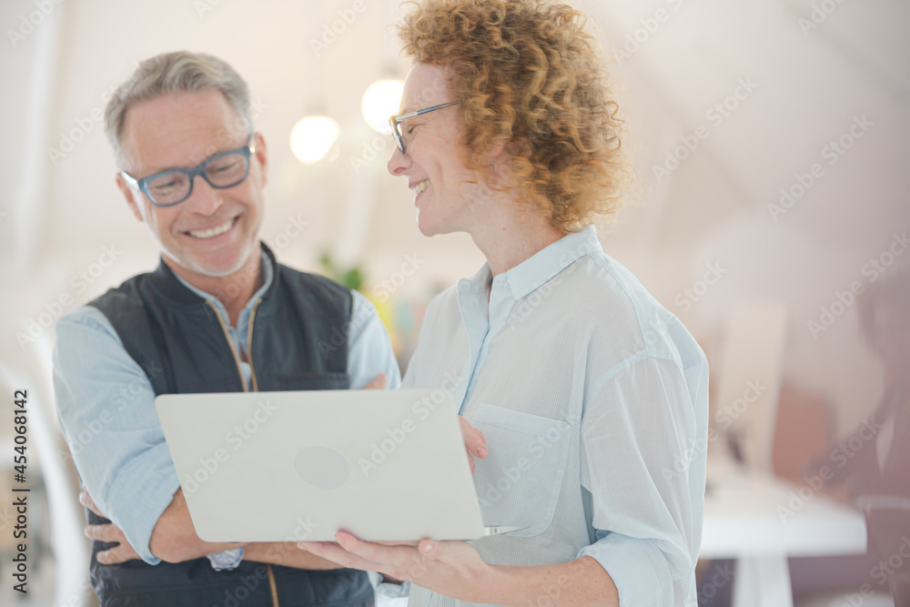 Portrait of man and woman with laptop, smiling in office