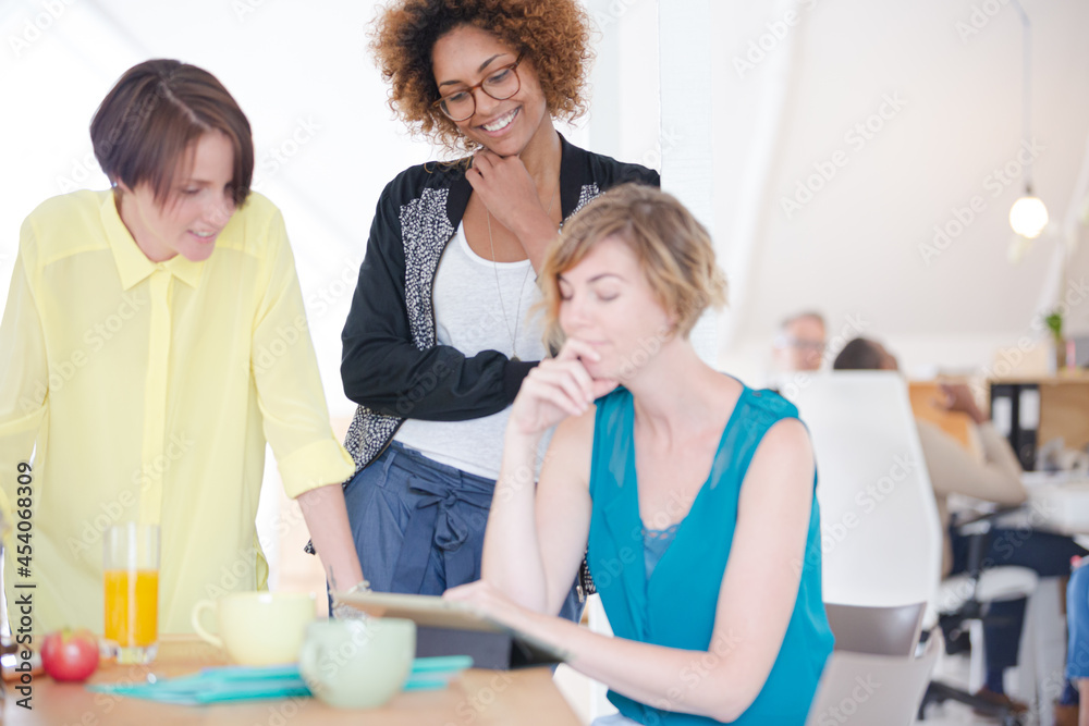 Women looking at digital tablet and smiling in office Women looking at digital tablet and smiling in office