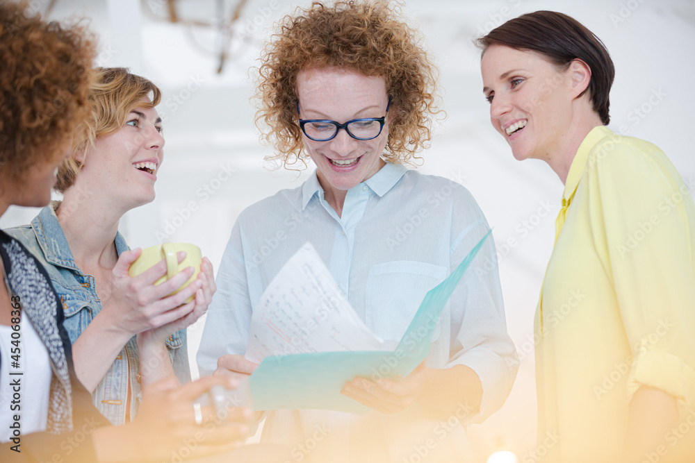 Women with coffe cup talking in office Women with coffe cup talking in office