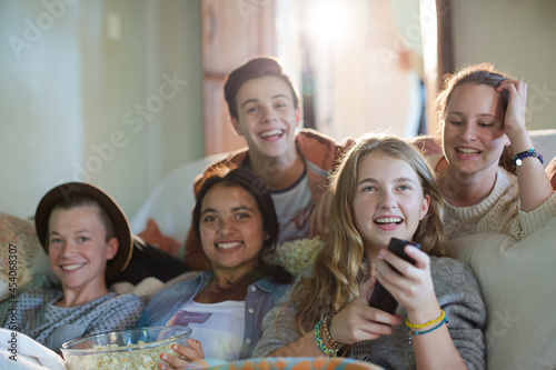 Group of teenagers having fun while watching tv on sofa