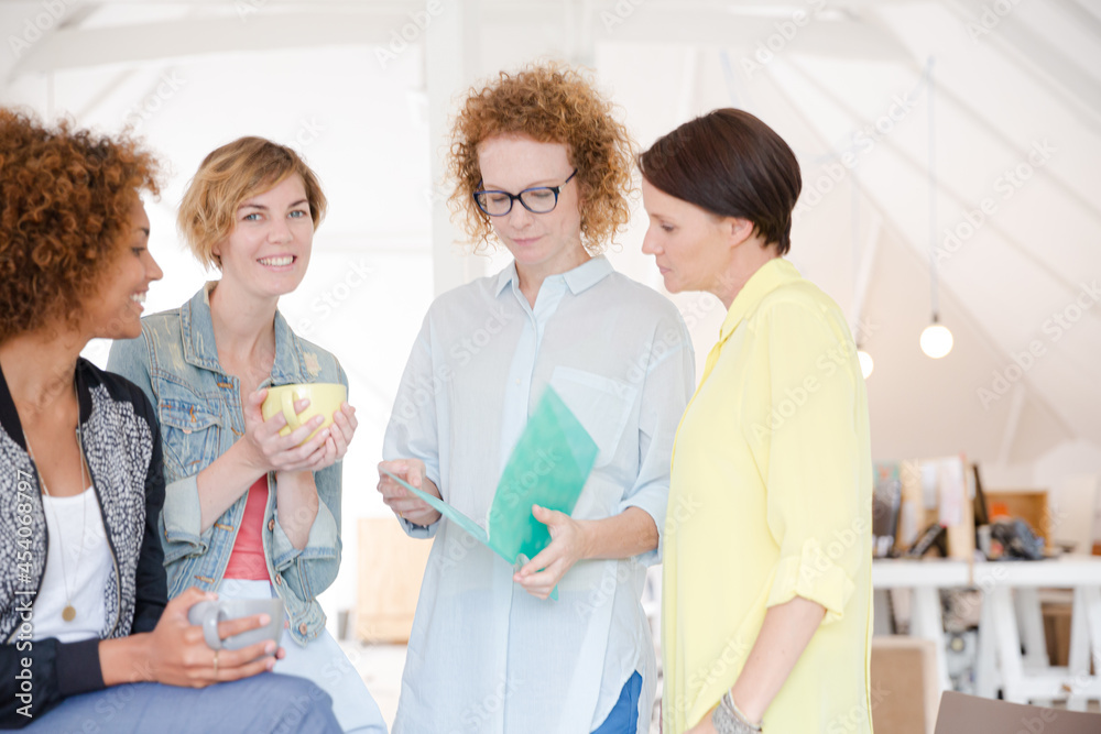 Women with coffe cup talking in office Women with coffe cup talking in office
