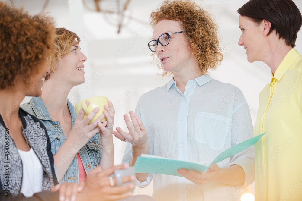 Women with coffe cup talking in office Women with coffe cup talking in office