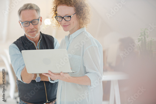 Portrait of man and woman with laptop, smiling in office