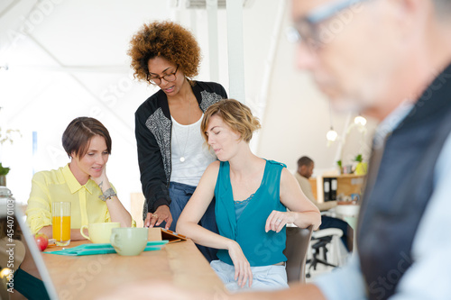 Women looking at digital tablet and smiling in office