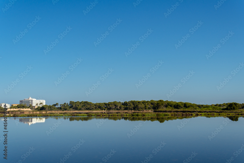 General view of the Mallorcan town of Colonia de Sant Jordi at sunrise reflected in the pond of the salt works