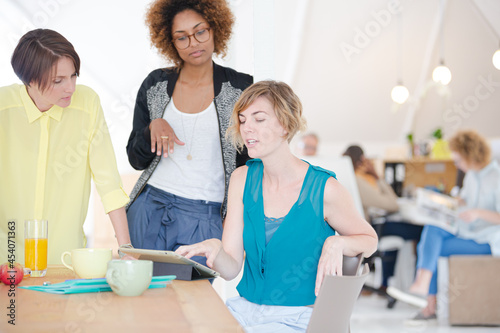 Women looking at digital tablet and smiling in office