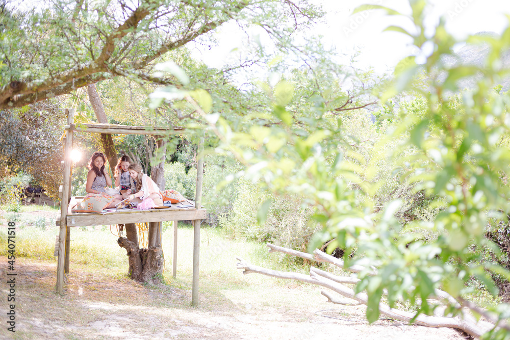 Naklejka premium Three teenage girls playing in tree house in summer