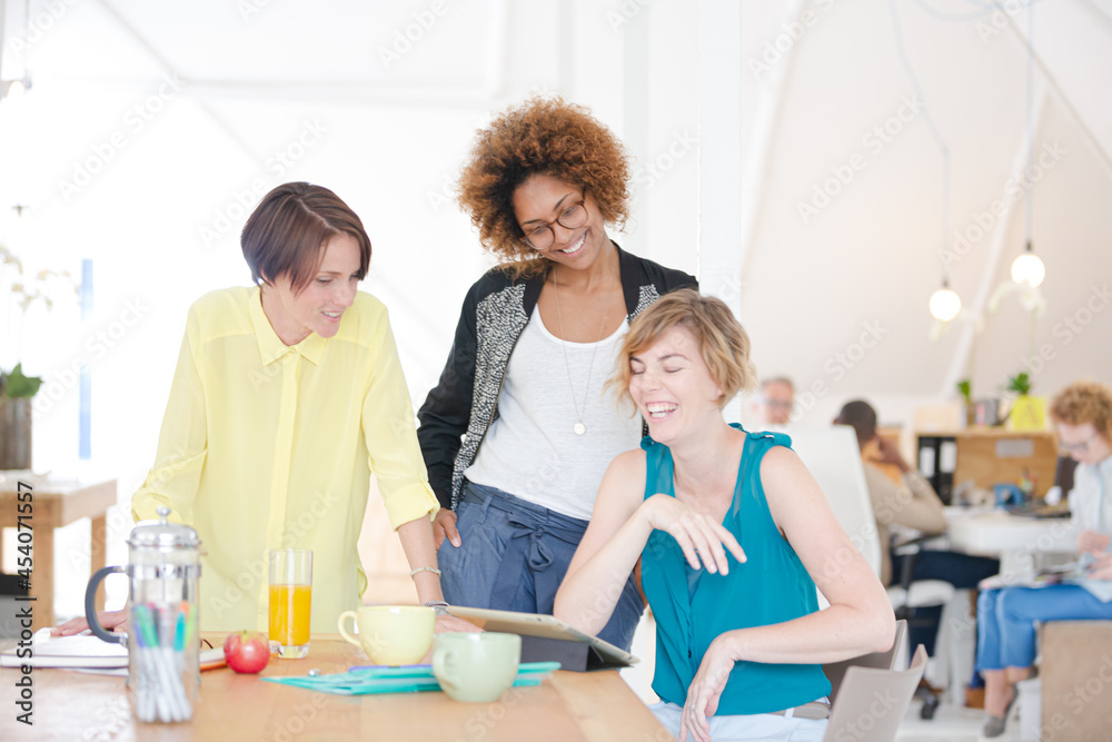 Women looking at digital tablet and smiling in office Women looking at digital tablet and smiling in office