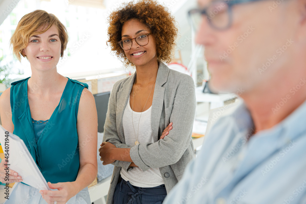 Fototapeta premium Colleagues talking and smiling in office, holding documents