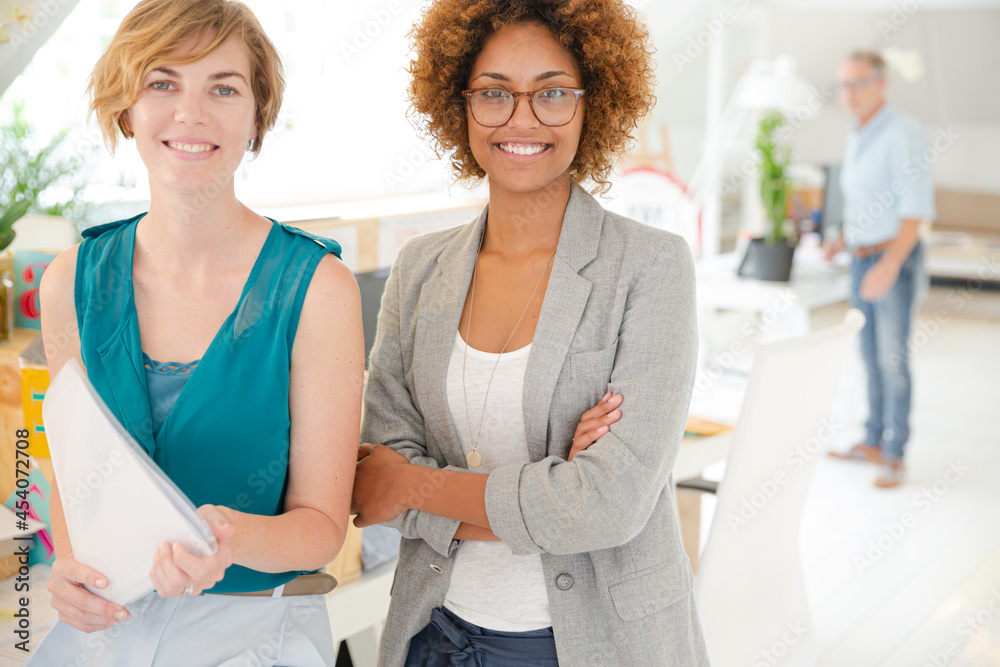 Obraz premium Women smiling in office, holding documents