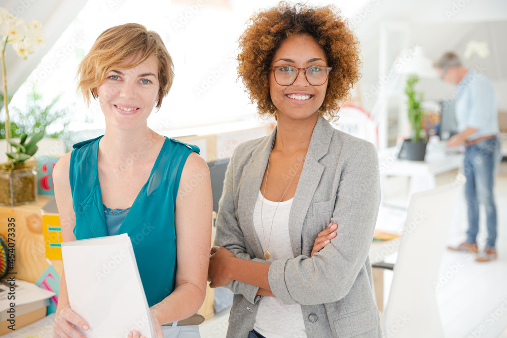 Women smiling in office, holding documents Women smiling in office, holding documents