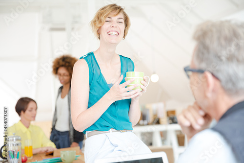 Man and woman sitting in office,smiling and talking