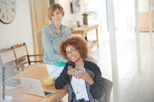 Portrait of women smiling in office with laptop on desk