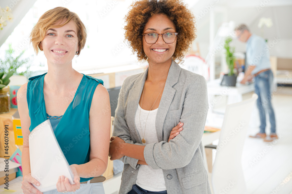 Women smiling in office, holding documents Women smiling in office, holding documents