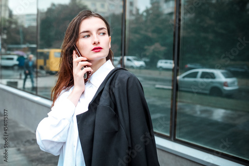 Portrait of successful woman with smartphone on background of office building