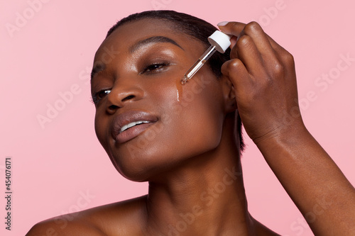 Young woman applying face serum