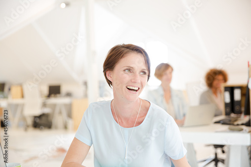 Portrait of woman sitting at desk in office and smiling Free Download Portrait of woman sitting at desk in office and smiling - GFXLoad