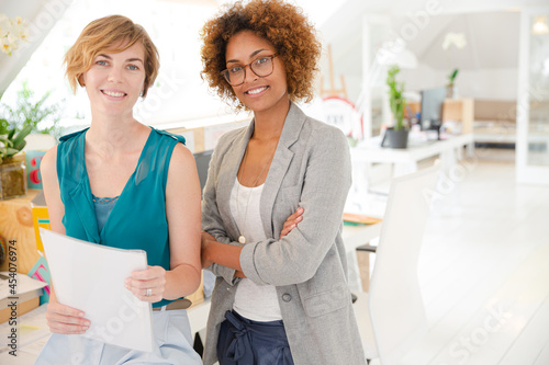 Women smiling in office, holding documents