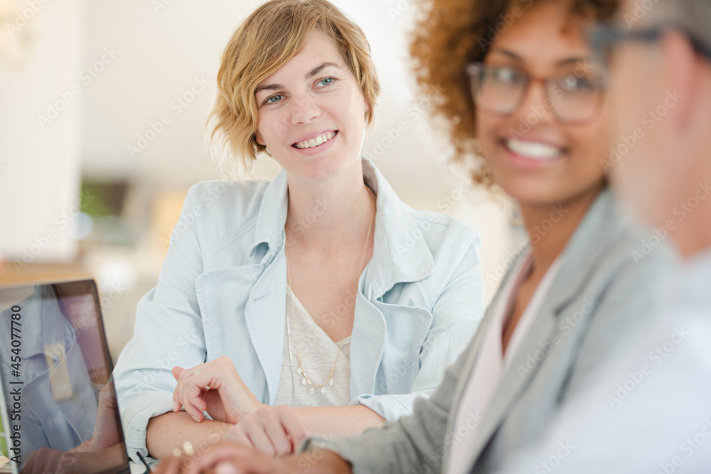 Fototapeta premium Three office workers talking at desk with laptop