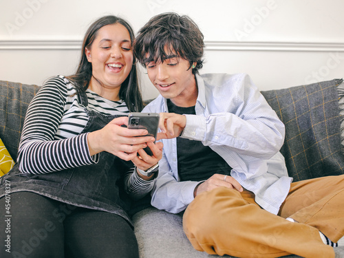 Valokuva Brother and sister sitting on sofa and using smart phone