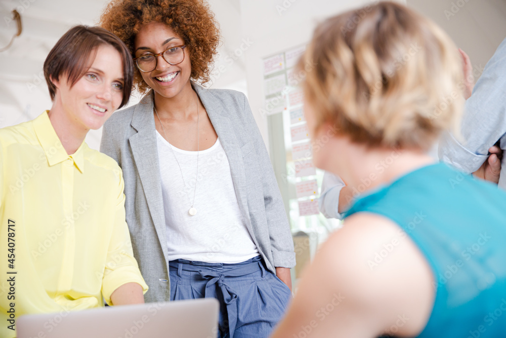Fototapeta premium Portrait of women smiling in office with laptop on desk