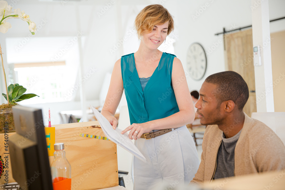 Obraz premium Woman and man looking at documents, talking and smiling in office