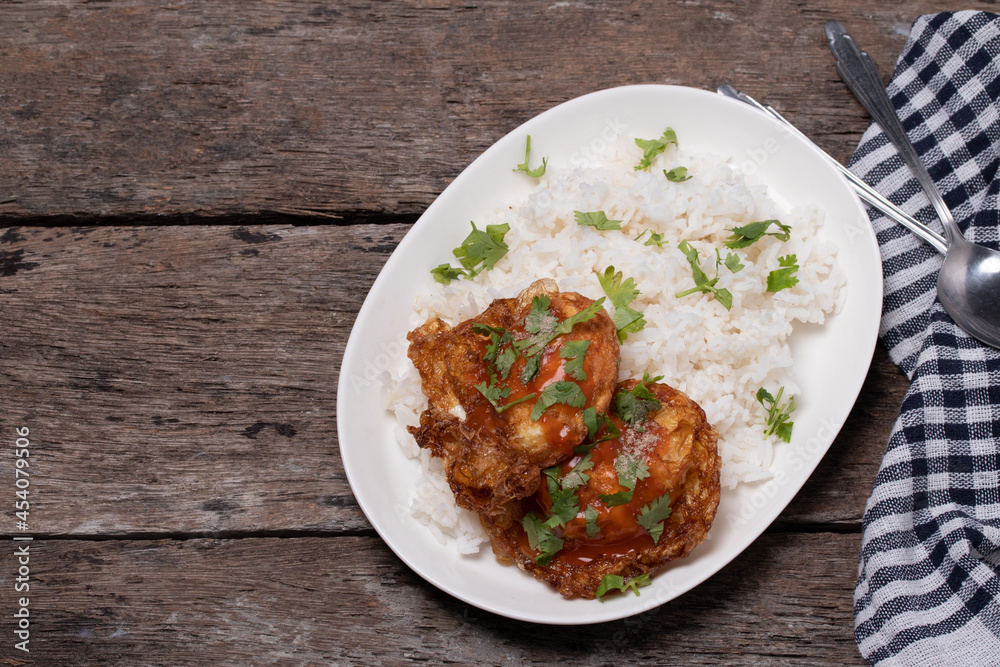Crispy fried eggs and steamed rice in a white plate on the wooden floor. Crispy fried eggs and steamed rice in a white plate on the wooden floor.