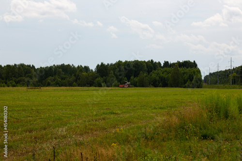 a field in August, an agricultural tractor is visible in the distance © Anna