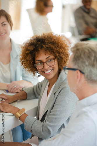 Three office workers talking at desk with laptop