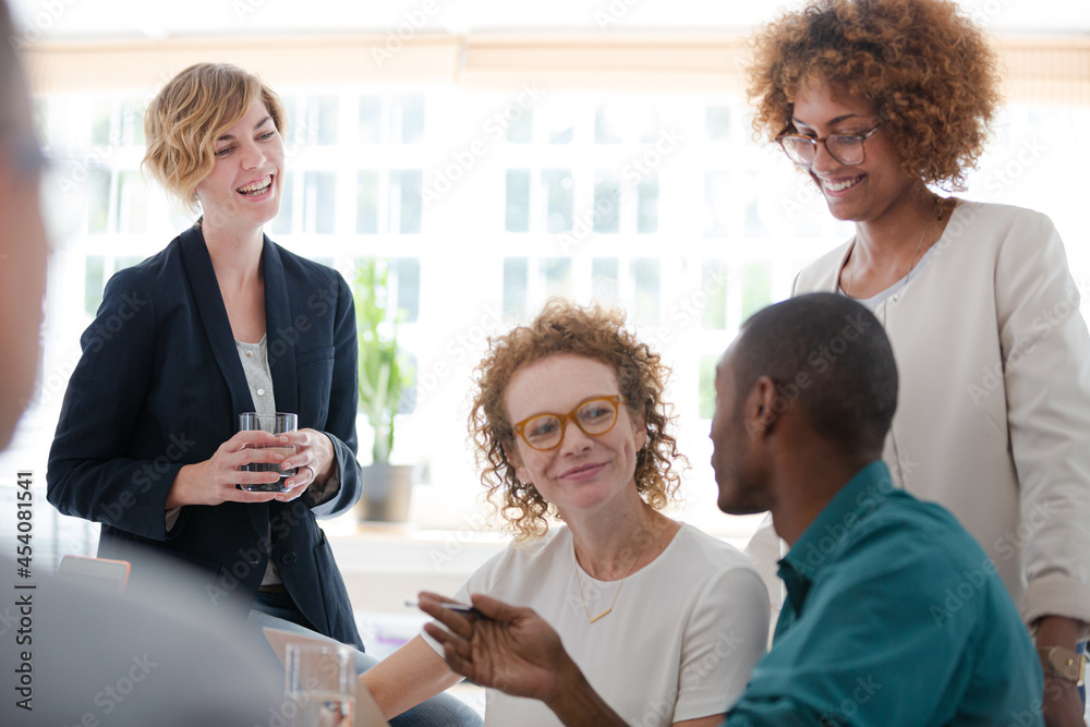 Office workers talking and smiling at desk Office workers talking and smiling at desk