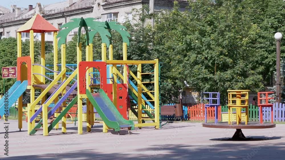 Rotation of an Empty Multicolored Carousel on a Playground in a City Park. Deserted park in summertime. People, children stay at home on self-isolation. Pandemic, quarantine, covid-19. Zoom. Rotation of an Empty Multicolored Carousel on a Playground in a City Park. Deserted park in summertime. People, children stay at home on self-isolation. Pandemic, quarantine, covid-19. Zoom.