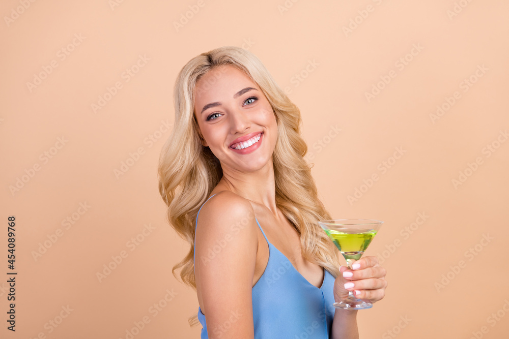 Profile side photo of young cheerful woman happy positive smile drink cocktail glass isolated over beige color background Profile side photo of young cheerful woman happy positive smile drink cocktail glass isolated over beige color background