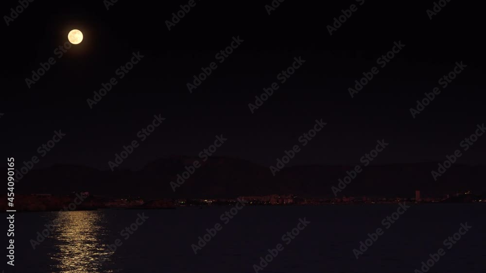 Full moon at night on black sky over sea, coastal region. Moonlight reflecting in water. Full moon at night on black sky over sea, coastal region. Moonlight reflecting in water.