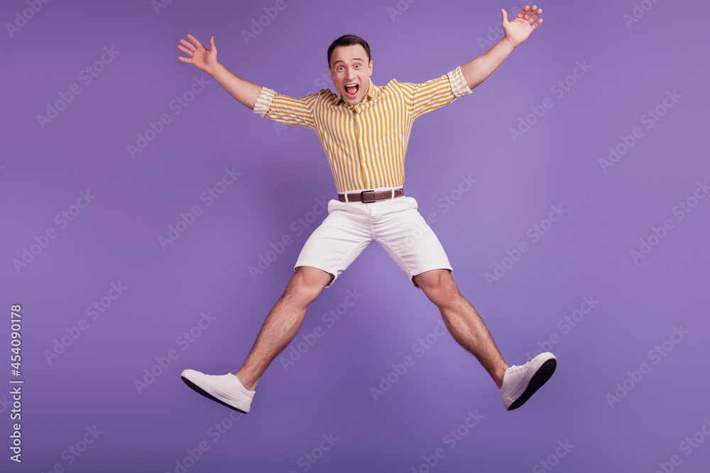 Portrait of crazy astonished guy jump star pose dance on purple background