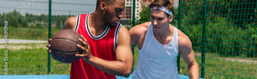 African american man playing streetball with friend outdoors, banner