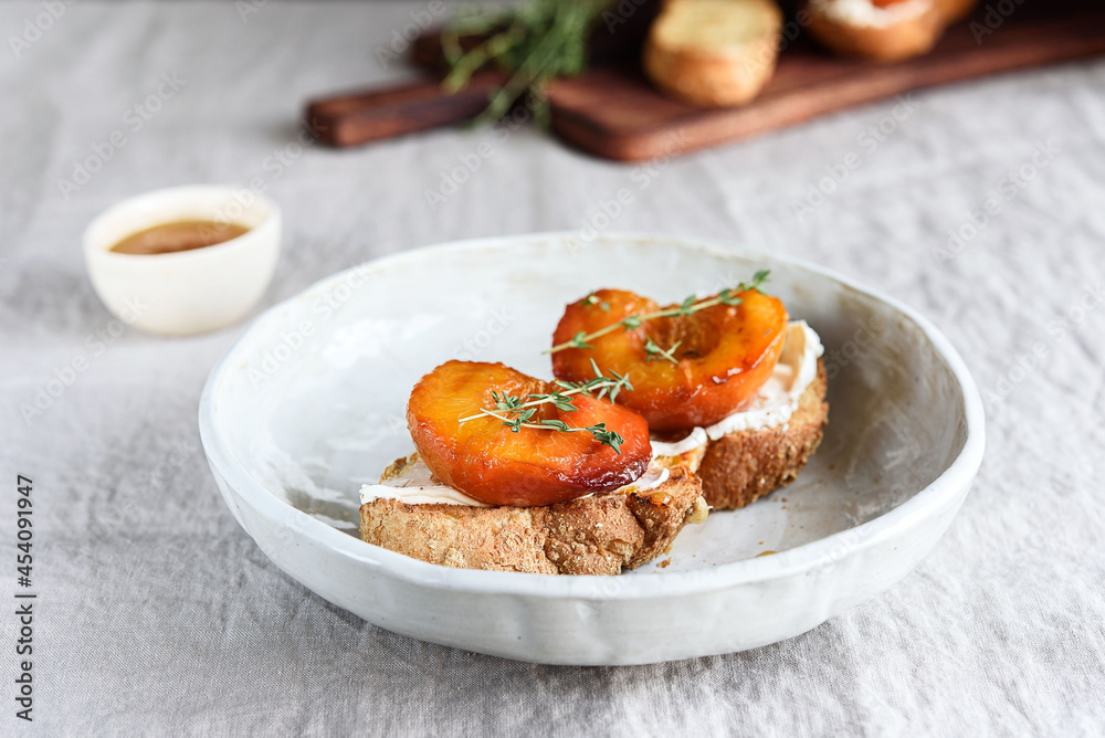Summer Breakfast - toast (sandwich, bruschetta) with grilled peaches, cream cheese (ricotta, mascarpone), thyme and honey on beige linen tablecloth. Selective focus Summer Breakfast - toast (sandwich, bruschetta) with grilled peaches, cream cheese (ricotta, mascarpone), thyme and honey on beige linen tablecloth. Selective focus
