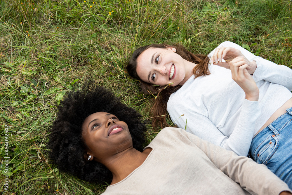 Smiling young female friends lying in park Smiling young female friends lying in park