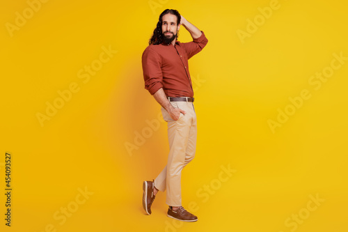 Portrait of charming macho handsome guy hand pocket posing on yellow background