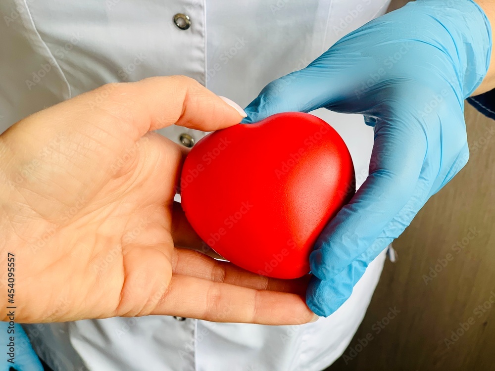 Red heart in hands in blue medical gloves. Red heart in hands in blue medical gloves.
