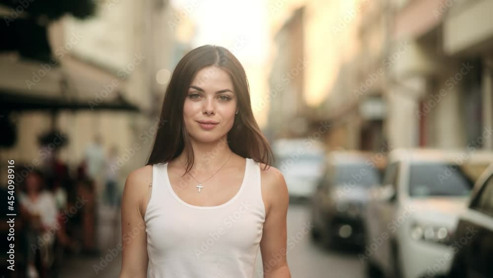 Happy young beautiful woman walking on the street. Portrait of cheerful girl looking at camera. Portrait of a Gorgeous Dark Haired Woman Smiling Charmingly Happy young beautiful woman walking on the street. Portrait of cheerful girl looking at camera. Portrait of a Gorgeous Dark Haired Woman Smiling Charmingly