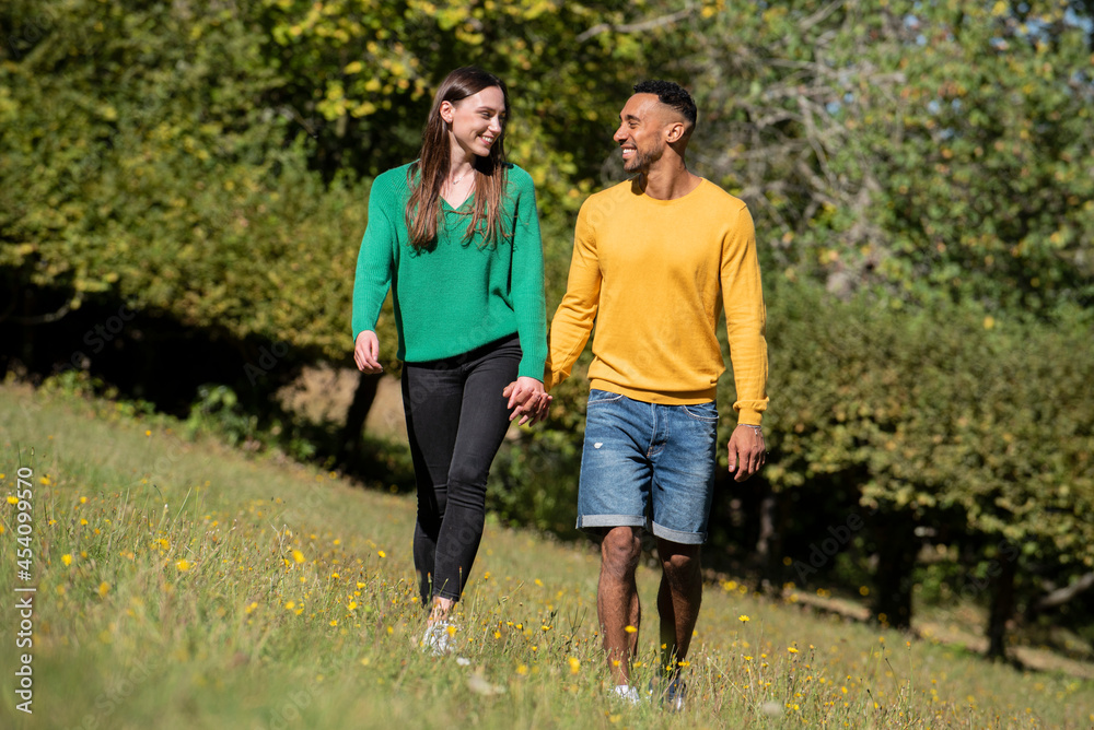 Smiling young couple walking in public park Smiling young couple walking in public park