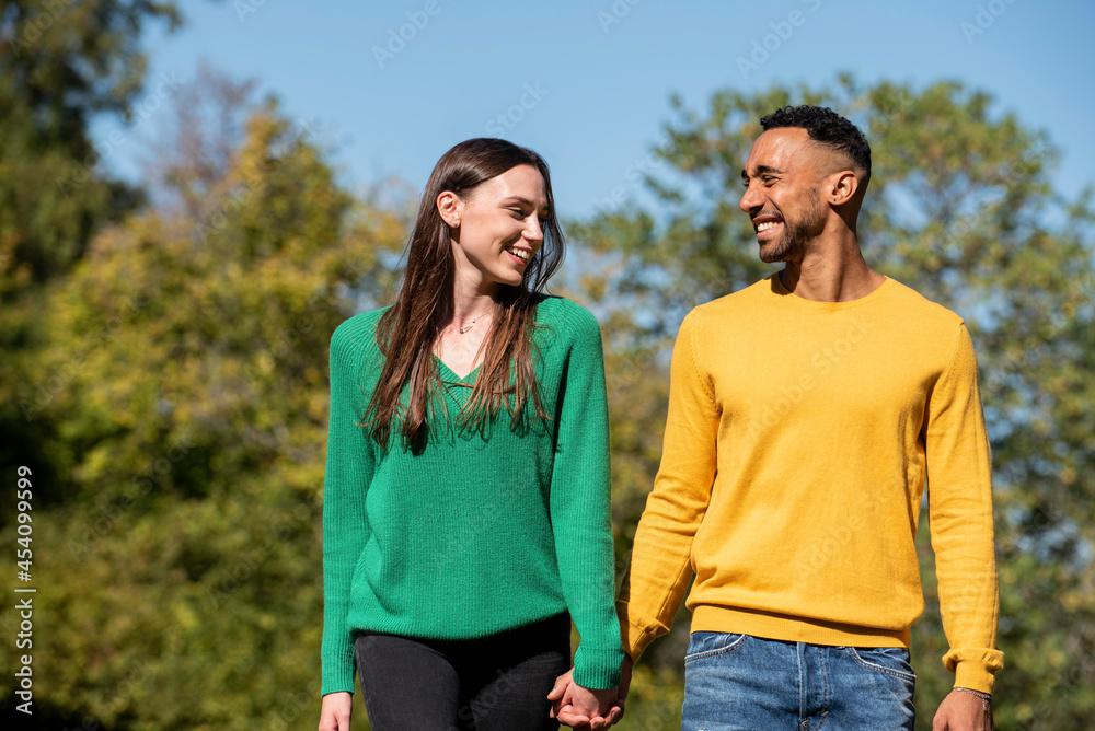 Smiling young couple walking in public park Smiling young couple walking in public park