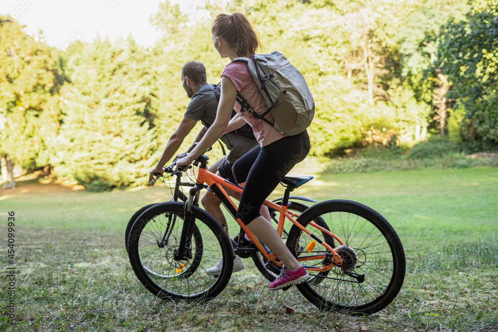 Young couple cycling bicycles in forest Young couple cycling bicycles in forest