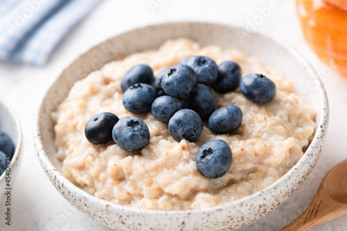 Oatmeal porridge with blueberries in a bowl, closeup view. Healthy vegetarian breakfast for weight loss, clean eating diet