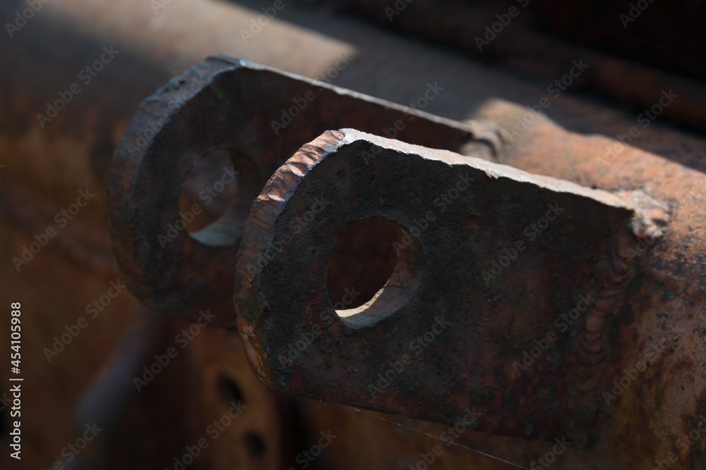 Close-up of an old rusty traverse of a rotten tow truck with two metal eyelets